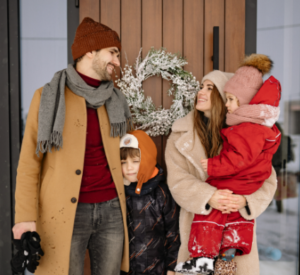 A happy family standing together outside their front door, symbolizing homeownership and real estate market insights from a local mortgage advisor.